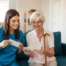 A caregiver reads cards with an older client, representing the fulfillment that comes with a career in home health care.