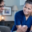 A nurse smiles as she helps an older couple with their medication in the comfort of their own home, showing the benefits of in-home nursing services.