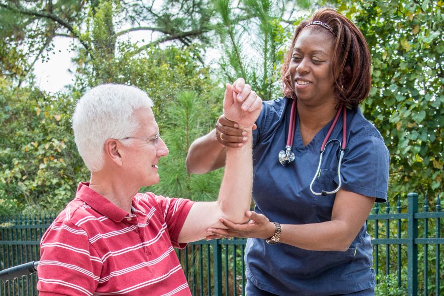 A health care provider assists an elderly man with rehab an upper body injury by stabilizing his shoulder. Occupational Therapy in Copperas Cove