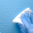 A gloved hand wipes down a surface, representing hygiene and practices that home health workers should employ.