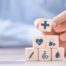 A stack of block with different health related icons represents health insurance which can help with home health care.